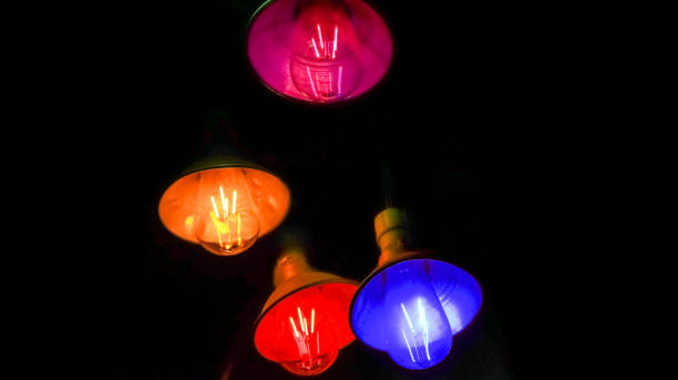 istock Colorful light bulbs hanging in the dark 1177588200