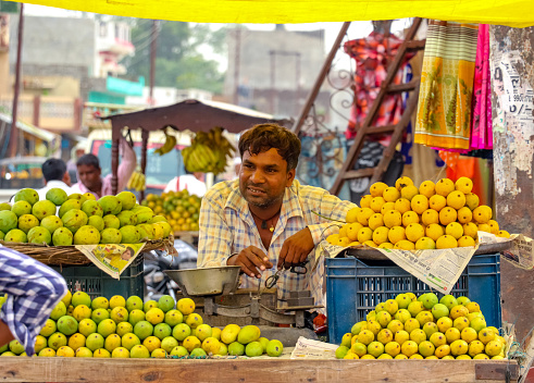 Nautanwa, India - June 14 2018: A middle-aged Indian fruit seller selling tropical fruits