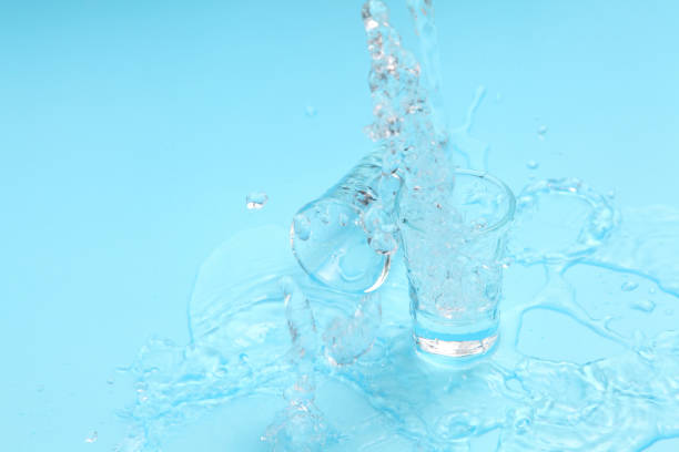 istock pouring vodka to shot glass on blue background with a blank space for a text, Russian vodka on color table 1177589455