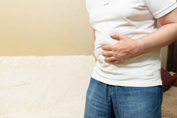 istock Man in white shirt holding his stomach 1177590416