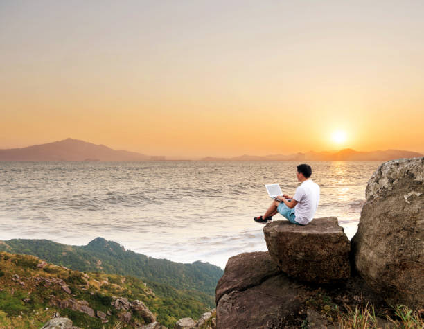 istock Man using laptop on top of the cliff 1177591668