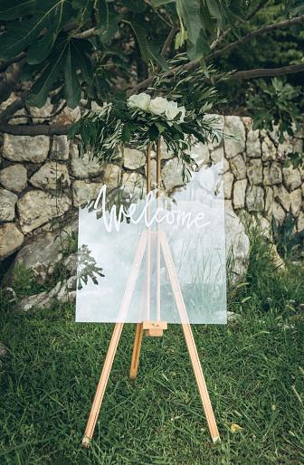 An easel decorated with flowers at a wedding event at which the inscription is welcome.