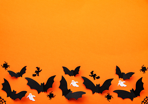 holidays  concept - halloween paper decorations and sweets with blank copy space over orange background