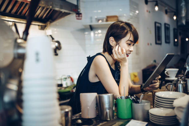 istock Young Asian female barista using a digital tablet while working behind a bar counter in a coffee shop 1177606395