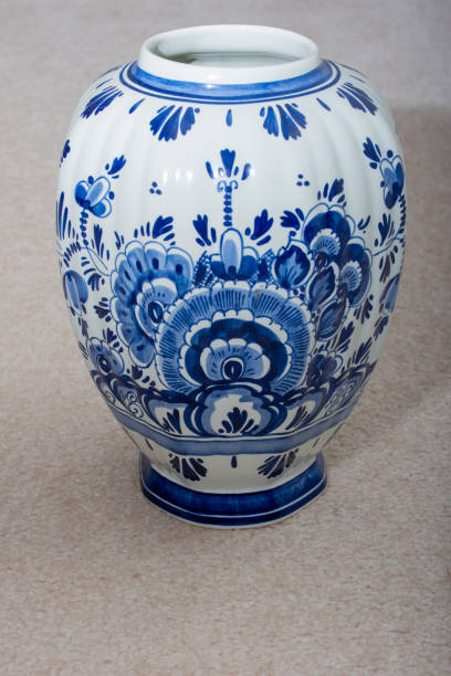 jarrón holandés delft blau (azul) hecho a mano con diseños azules y porcelana de porcelana sobre un fondo beige aislado. países bajos. - dutch culture delft souvenir blue fotografías e imágenes de stock