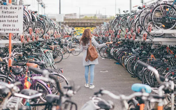 Photo of Rear view of the girl lost her bicycle at the bike parking in Eindhoven City (Netherlands) - bike chaos in Holland concept - Sign: 