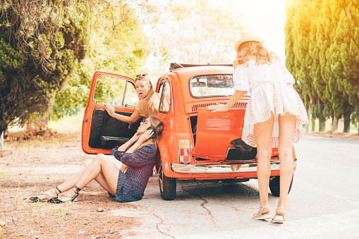 Funny picture of three women with red vintage car