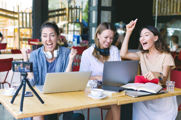 Three young millennials girls working together, making video coaching - concept of teamwork, content making and online freelance job. Youtuber recording an infoproduct with a webcam live broadcast