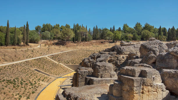 Land and ruins of the amphitheater, part of archaeological ensemble of Italica, Seville, Spain Land and ruins of the amphitheater, part of archaeological ensemble of Italica, city with a strategic role in the Roman Empire, birthplace of Emperors Trajan and Hadrian, in Santiponce, Seville, Spain. italica spain stock pictures, royalty-free photos & images