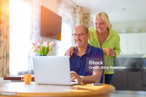 Senior Couple Looking At The Lap Top Screen Smiling And Drinking Coffee Elderly People Video Calling Or Talking By Web Camera Working At Home Freelancing And Having Hobbies Together Concept Stock Photo - Download Image Now