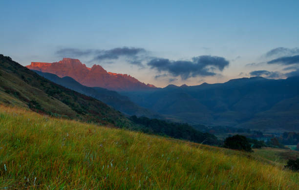 Sunrise over the cathkin Valley First light hits cathkin peak and champagne castle seen from the cathkin Valley drakensberg mountain range stock pictures, royalty-free photos & images