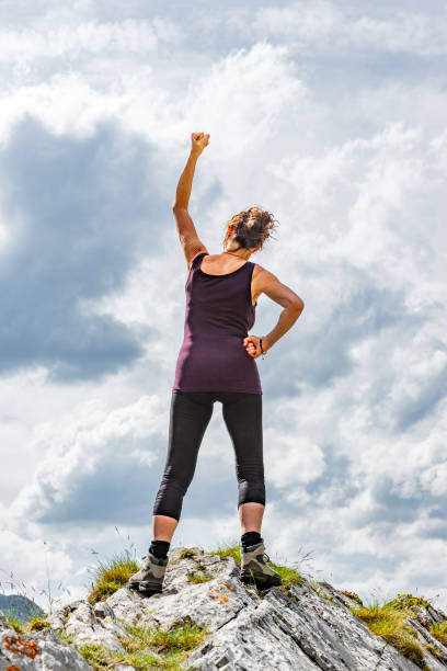 istock Female silhouette in winning pose on a mountain top 1177619654