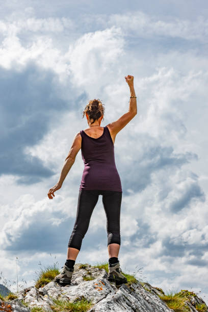 istock Female silhouette in winning pose on a mountain top 1177619684