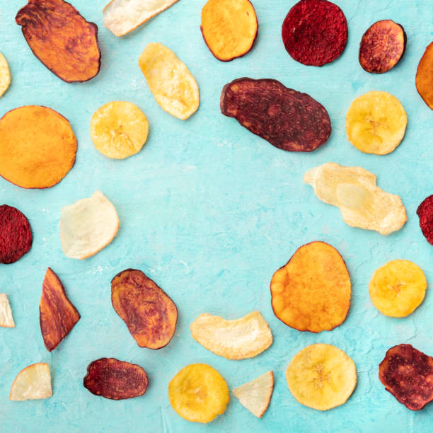 istock Dry fruit and vegetable chips on a teal blue background, forming a frame for copy space, overhead square shot 1177623603