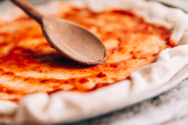 rozsiewanie sosu pomidorowego na patelni do pizzy - makes the dough zdjęcia i obrazy z banku zdjęć