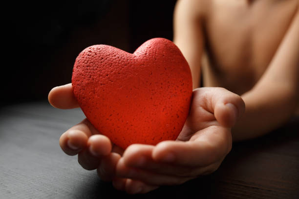 istock red heart in hands on a dark background 1177627899