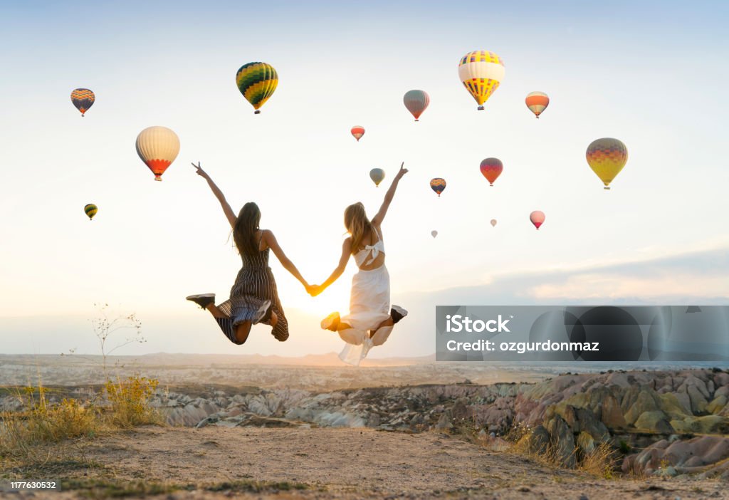 Girlfriends traveling and enjoying valley view at sunset in Cappadocia Hot Air Balloon Stock Photo
