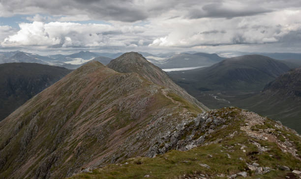 Buachaille Etive Beag ridge, on the ascent to Stob Dubh, with Loch Etive in the background and clouds in the sky. Glencoe, Highlands of Scotland Path traversing the ridge to Stob Dubh, peak of the Buachaille Etive Beag, in Glencoe, Highlands of Scotland. With Loch Etive in the background and clouds in the sky. Munro bagging. Hiking. Hill Walking buachaille etive beag photos stock pictures, royalty-free photos & images