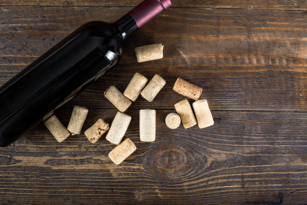 a bottle of red wine and many corks on a wooden background. - wine bottle wine wood bottle stopper imagens e fotografias de stock