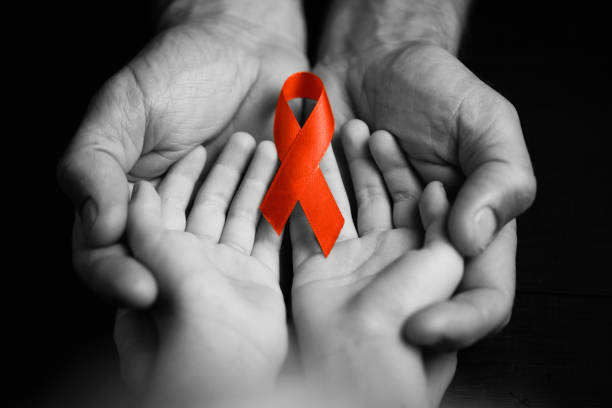 istock child with AID red ribbon on a dark background.black and white. 1177644142