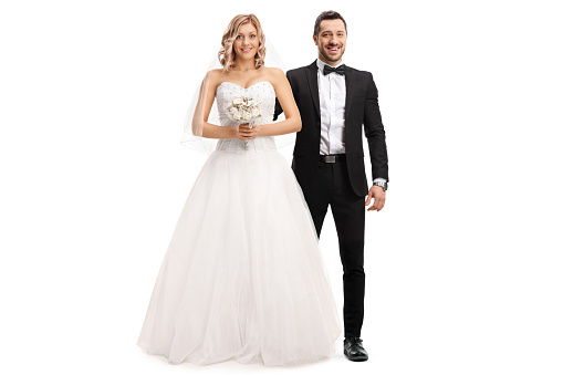 Full length portrait of a beautiful bride and a groom by her side isolated on white background