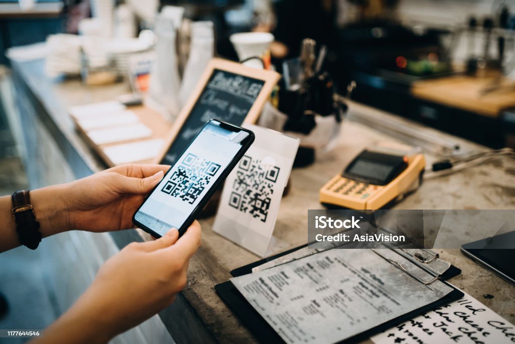 Customer scanning QR code, making a quick and easy contactless payment with her smartphone in a cafe QR Code Stock Photo