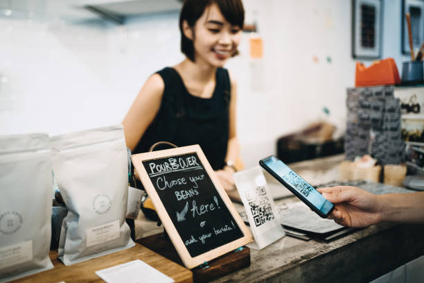 istock Customer scanning QR code, making a quick and easy contactless payment with her smartphone in a cafe in front of a smiling barista 1177644576