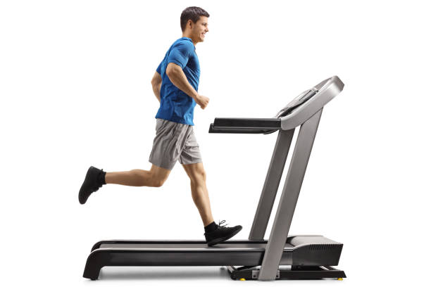 Guy running on a treadmill Full length profile shot of a guy running on a treadmill isolated on white background treadmill photos stock pictures, royalty-free photos & images