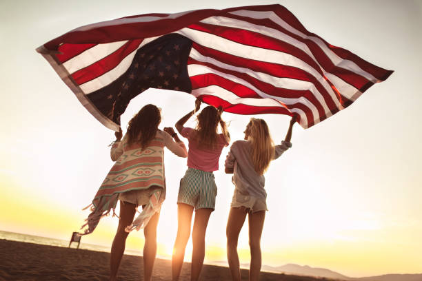 istock Young friends carrying american flag on the beach 1177646281