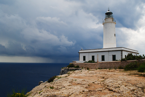Far de la Mola, lighthouse on the cliffs of Formentera. Dark clouds on the horizon announce an approaching storm.