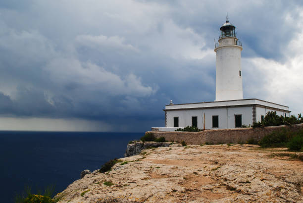 far de la mola, lighthouse on the cliffs of formentera an approaching storm. - storm lighthouse cloudscape sea imagens e fotografias de stock