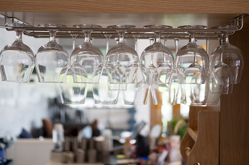Wine glasses stacked hanging above bar, nightclub or a restaurant with light shining through them