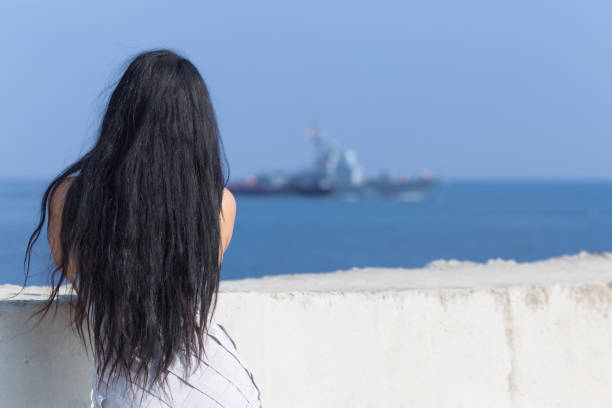 istock Dark haired female person observing floating military ship 1177652425
