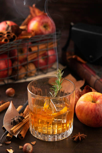 copa de bebida alcohólica de whisky con una rama de romero con humo y manzanas, palitos de canela. concepto de mágico otoño ambiente relajado y acogedor. - barra escocia fotografías e imágenes de stock