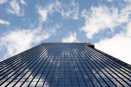 Bottom view of glass skyscraper, reflecting blue sky