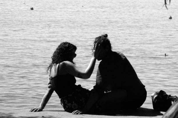 Ohrid, Macedonia, - September 22, 2019. Couple sitting at the water edge of lake Ohrid on a warm summer day.