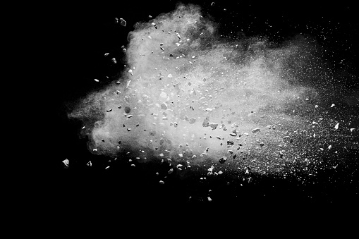 istock Split debris of stone exploding with white powder against black background. 1177670650