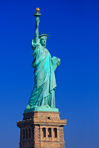 The statue of Liberty with yellow water taxi boat on the foreground, New York City, USA