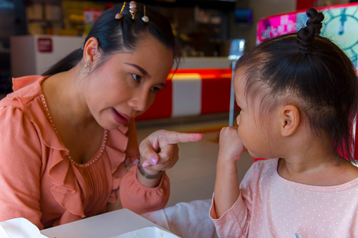 Angry mom with her child,  looking her daughter and complaining.