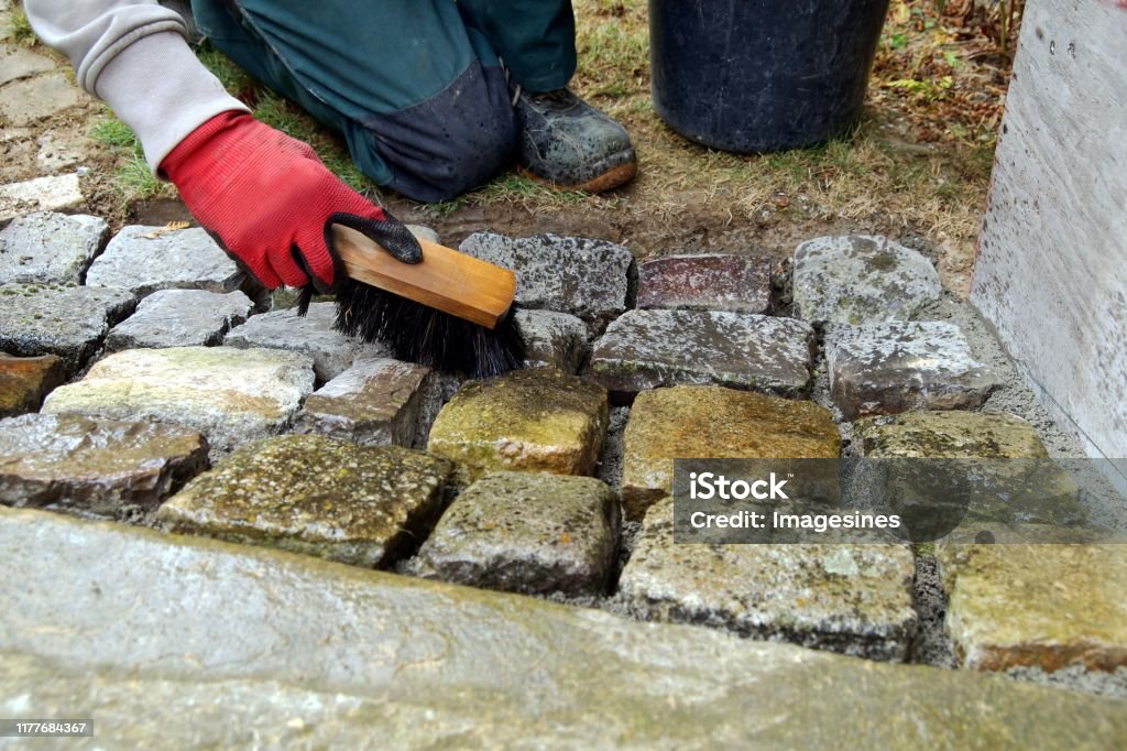 Pavement Works Cobbled Pavement Natural Stone Gloved Hands Of Worker  Cleaning Concrete Paver Blocks With Brush And Water After Laying Paving  Stones Carefully Placing In Cement Stock Photo - Download Image Now 