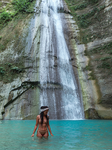woman alone at Tropical Waterfall turquoise pool at the middle of the jungle in Dao Falls in Cebu, Philippines