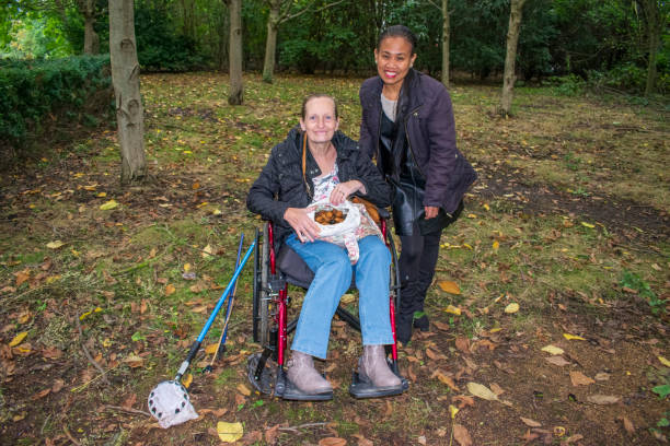 Disabled Female and Asian Friend Picking Walnuts, Caregiver, Carer, Real, Healthcare stock photo