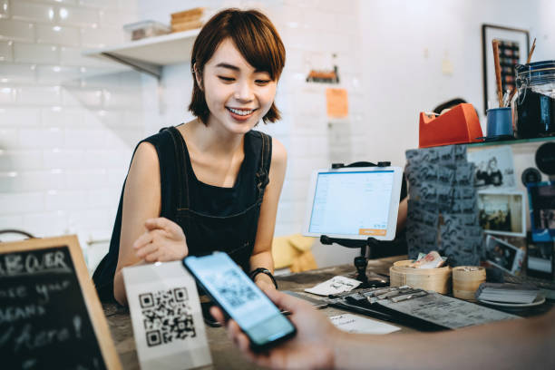 istock Customer scanning QR code, making a quick and easy contactless payment with her smartphone in a cafe in front of a smiling barista 1177690224