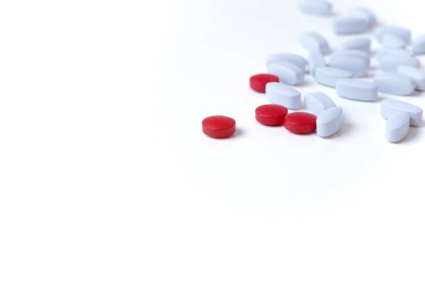 istock Single red pill shown prominently among light blue pills on white background. 1177702725