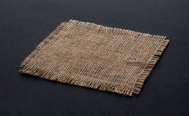 Old burlap fabric napkin on black background