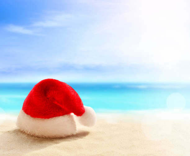 istock Christmas holidays concept. Santa claus hat on summer sand beach 1177705701