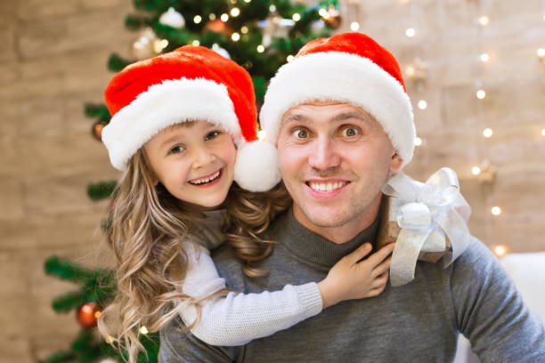 istock Dad and daughter, Christmas hat, tree, gift box 1177708136
