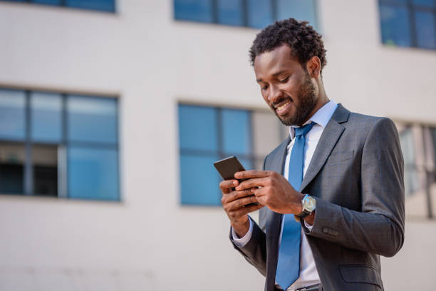 istock cheerful african american businessman smiling while using smartphone 1177710860