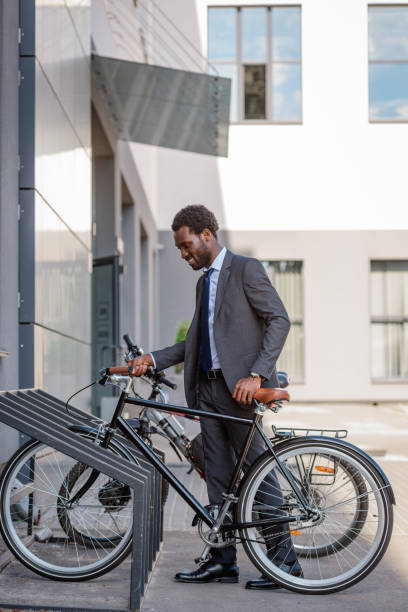 istock handsome african american businessman smiling while taking bicycle from parking 1177710867