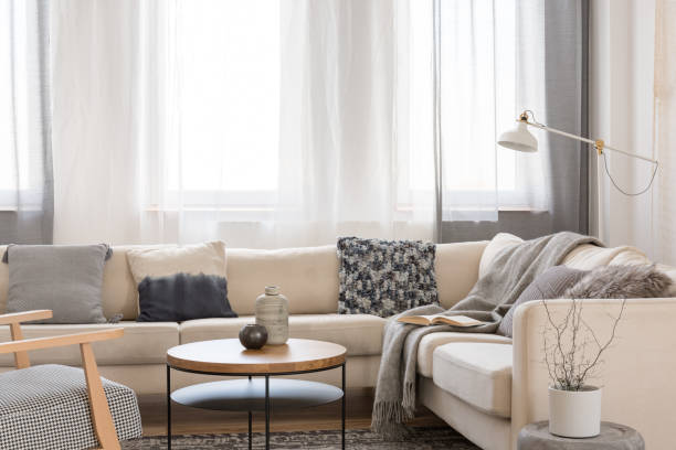 istock Beige comfortable corner sofa with grey pillows in elegant living room interior with white wall 1177720758